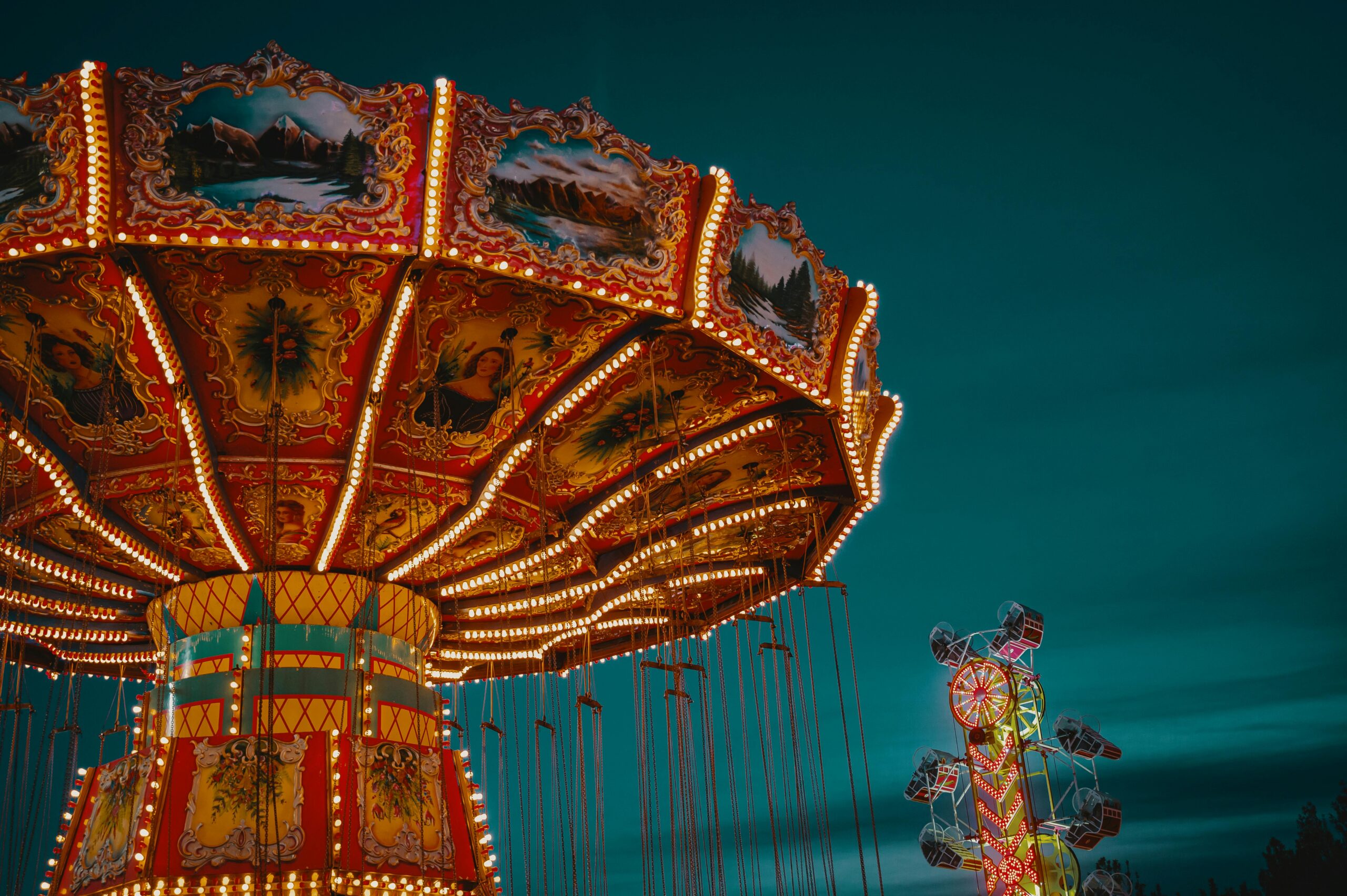 Brightly illuminated carousel at an amusement park during the evening, evoking a sense of fun and leisure.